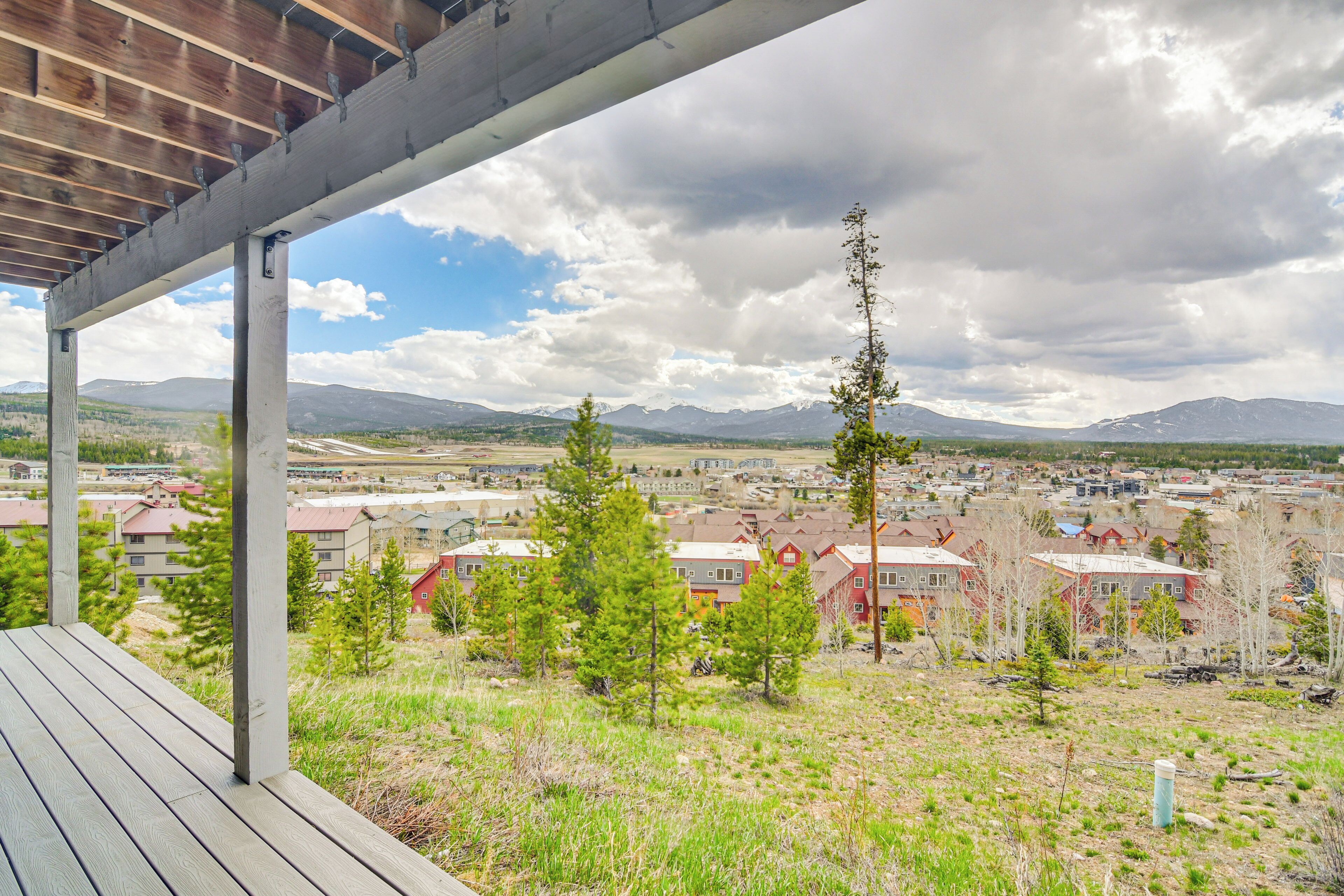 A covered outdoor area with a view of a residential neighborhood, including houses and mountains in the background.