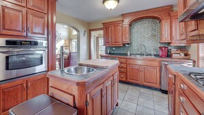 A kitchen with wooden cabinets, a stainless steel oven, a sink, and a herringbone tile backsplash. - Family-friendly Fischer Home w/ Private Hot Tub! (Canyon Lake)