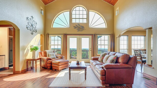 A spacious living room with a high ceiling, large windows, and a view of the outdoors. - Family-friendly Fischer Home w/ Private Hot Tub! (Canyon Lake)