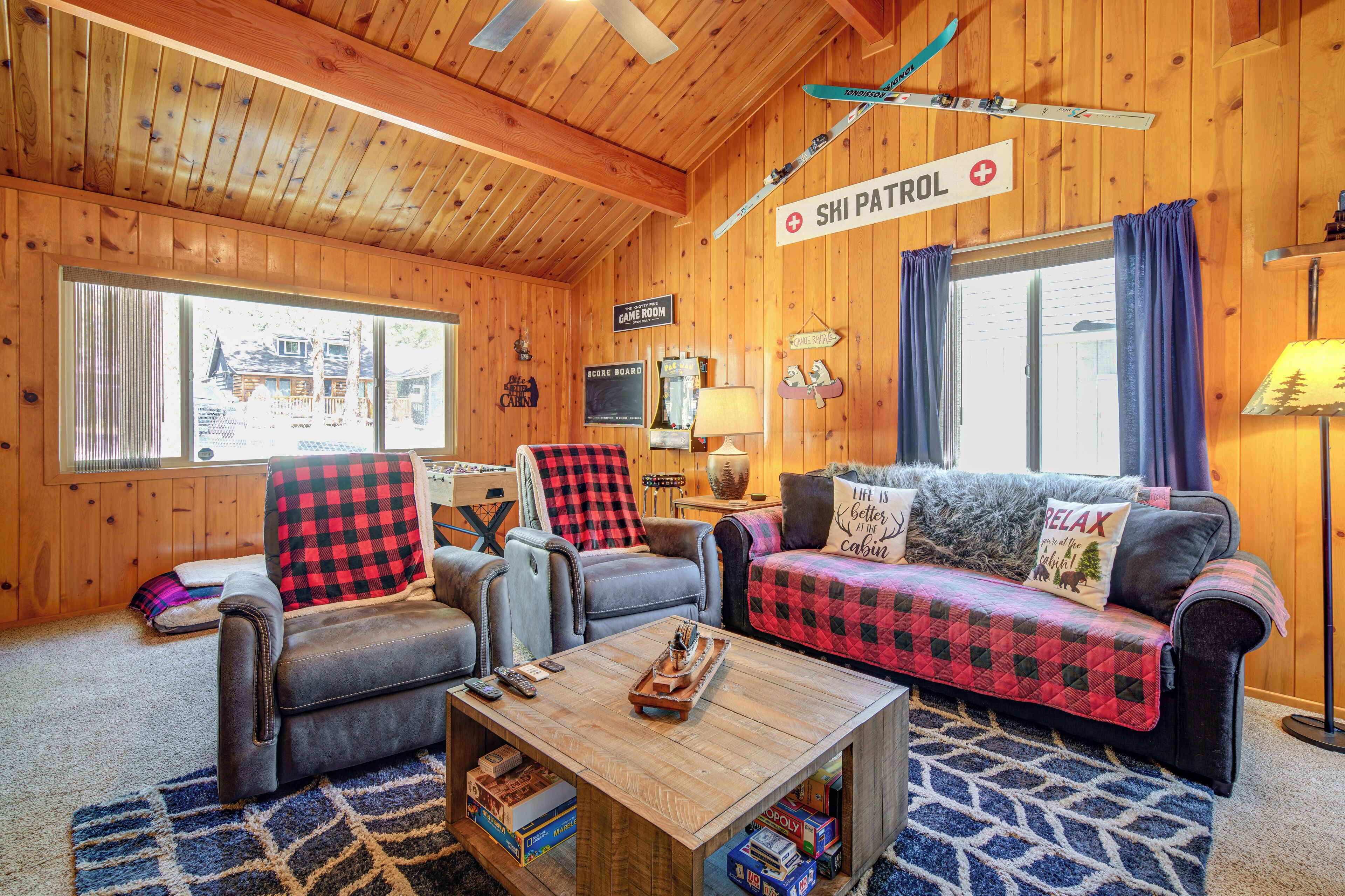 Ein gemütliches Blockhauss-Interieur mit Holzbalkendecke, einer Couch, einem Sessel, einem Couchtisch und einem Schild der Skiregierung.