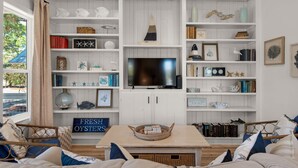 A living room with a TV, bookshelves, and a sign that reads "FRESH OYSTERS". - Beautiful House With Private Heated Pool & Golf Cart - 30a/seagrove Beach (Santa Rosa Beach)