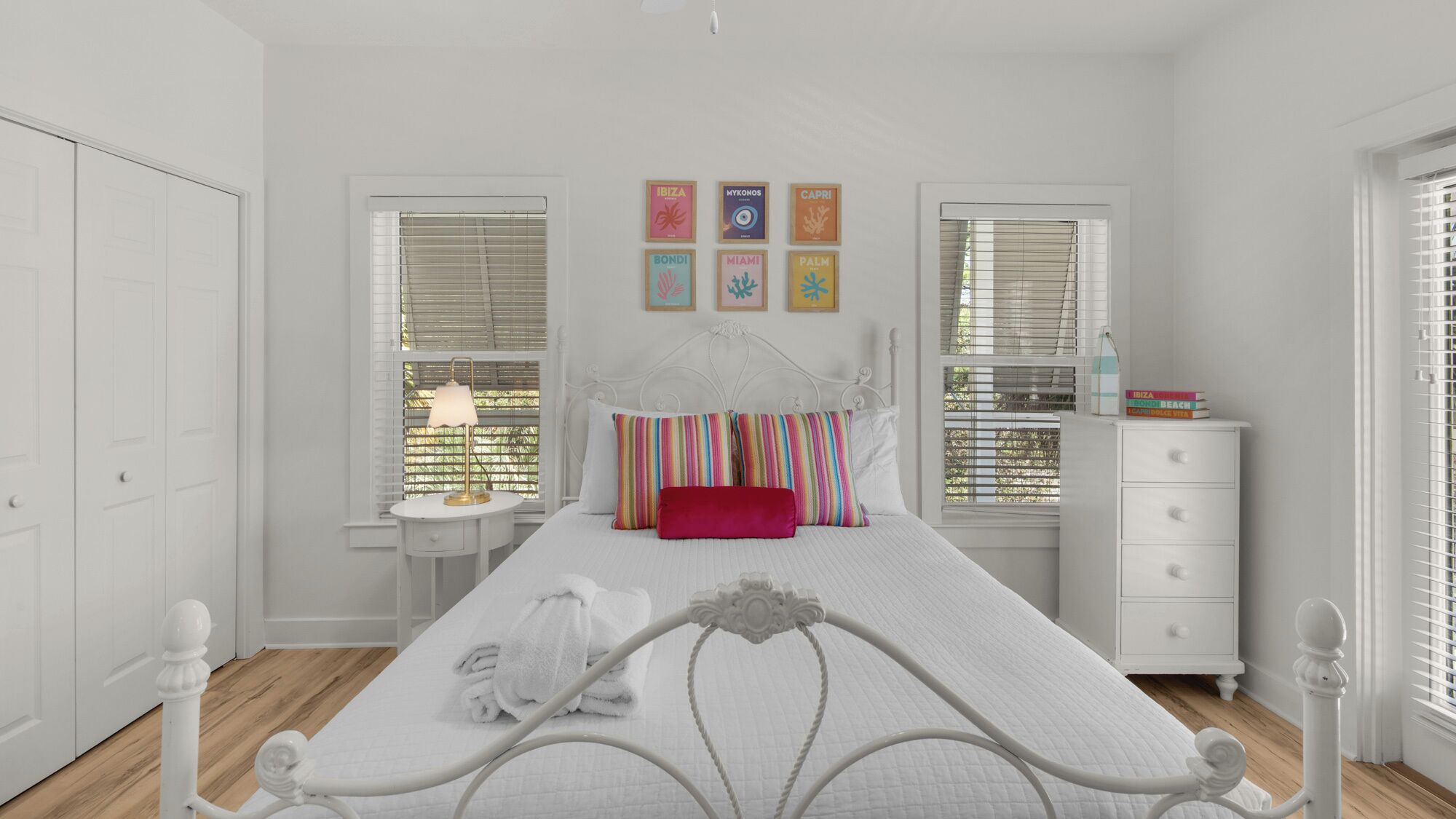 A bedroom with a bed, bedside tables, a dresser, and a window with blinds.