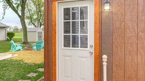 A white door with a glass panel and a small window above it, set in a wooden frame. - Port Clinton Home: Hot Tub, Steps to Portage River (Port Clinton)