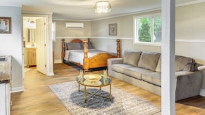 A bedroom with a bed, a sofa, a glass coffee table, and a rug. - Port Clinton Home: Hot Tub, Steps to Portage River (Port Clinton)