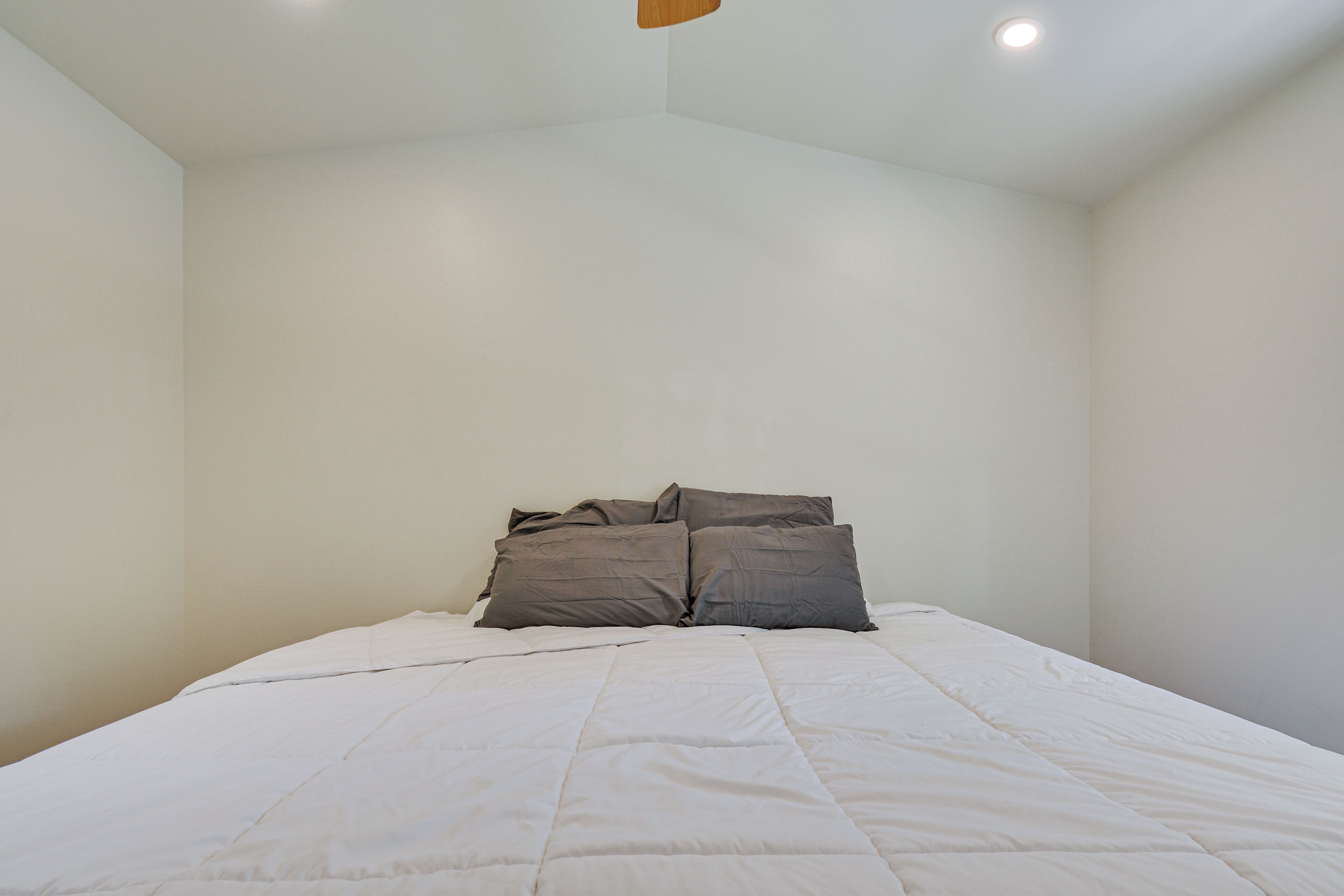 A bedroom with a bed, white walls, and a ceiling light.