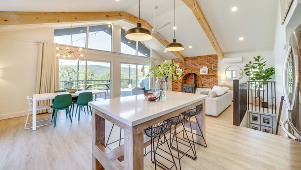 A spacious kitchen with a large island, wooden beams, and a brick wall. - Pine Cabin w/ Large Deck & Scenic Mountain Views! (Pine)