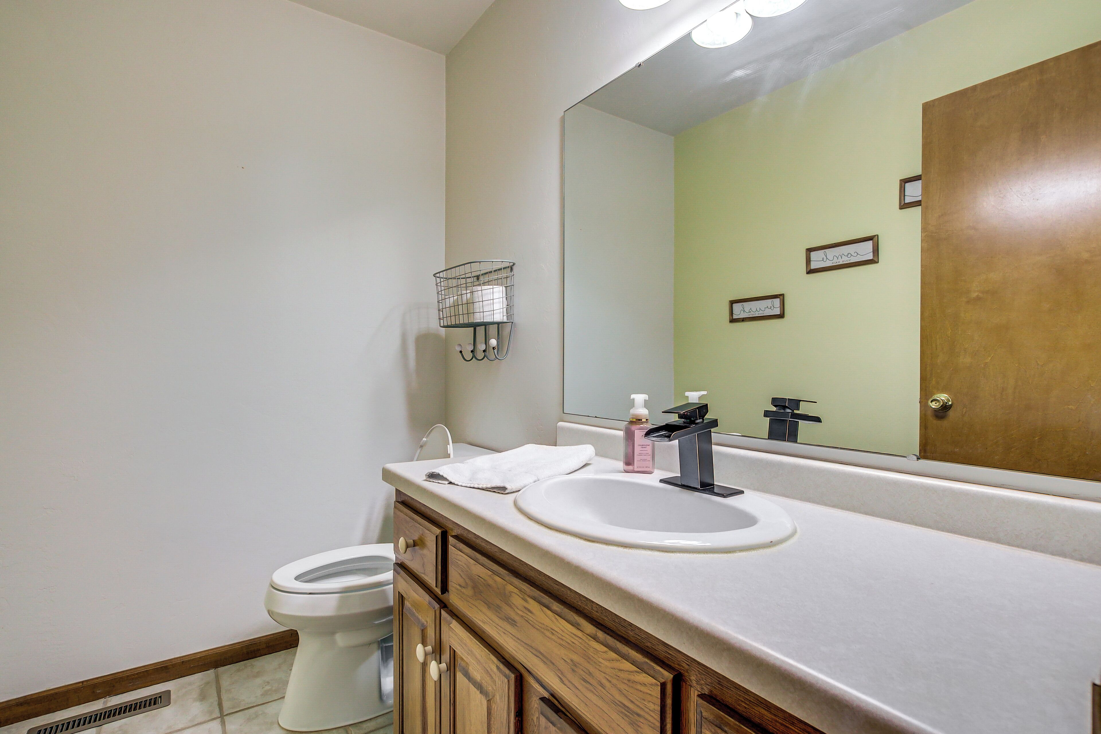 Ein Badezimmer mit Toilette, Waschbecken mit Spiegel und Holzschrank.