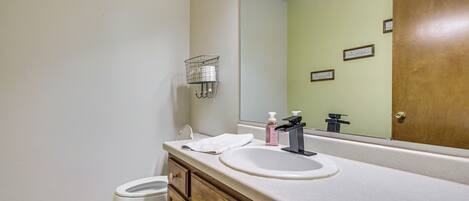 Ein Badezimmer mit Toilette, Waschbecken mit Spiegel und Holzschrank.