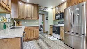 A kitchen with wooden cabinets, a stainless steel refrigerator, a microwave, and a washing machine. - Door County Townhome: Pool Access, 1 Mi to Beach! (Egg Harbor)