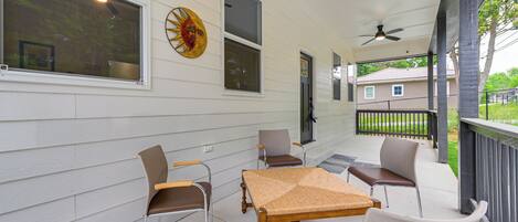 A covered porch with a table and chairs, a ceiling fan, and a decorative sun on the wall.