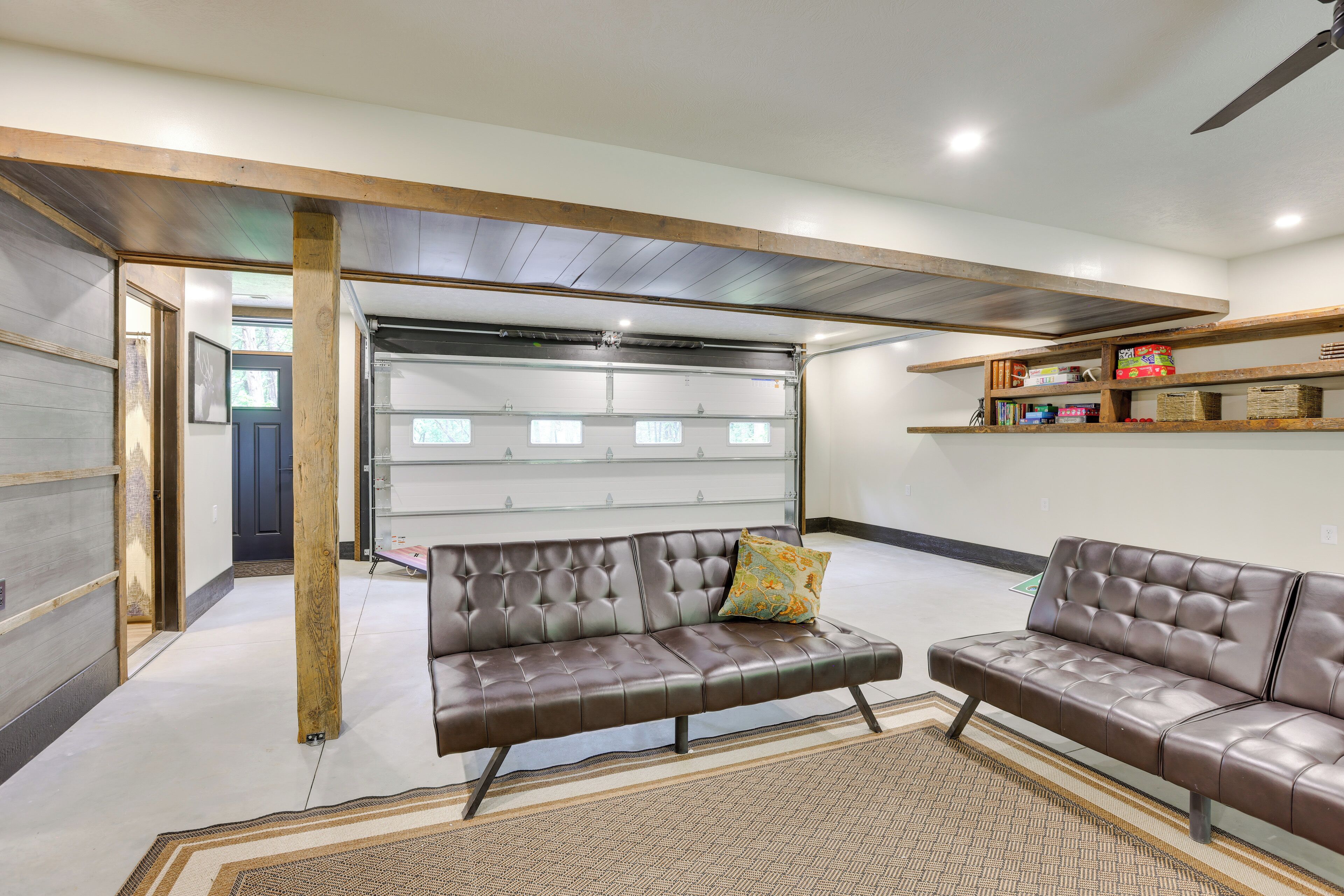 A modern living room with a leather sofa, a patterned rug, and wooden shelves with books and decorative items.