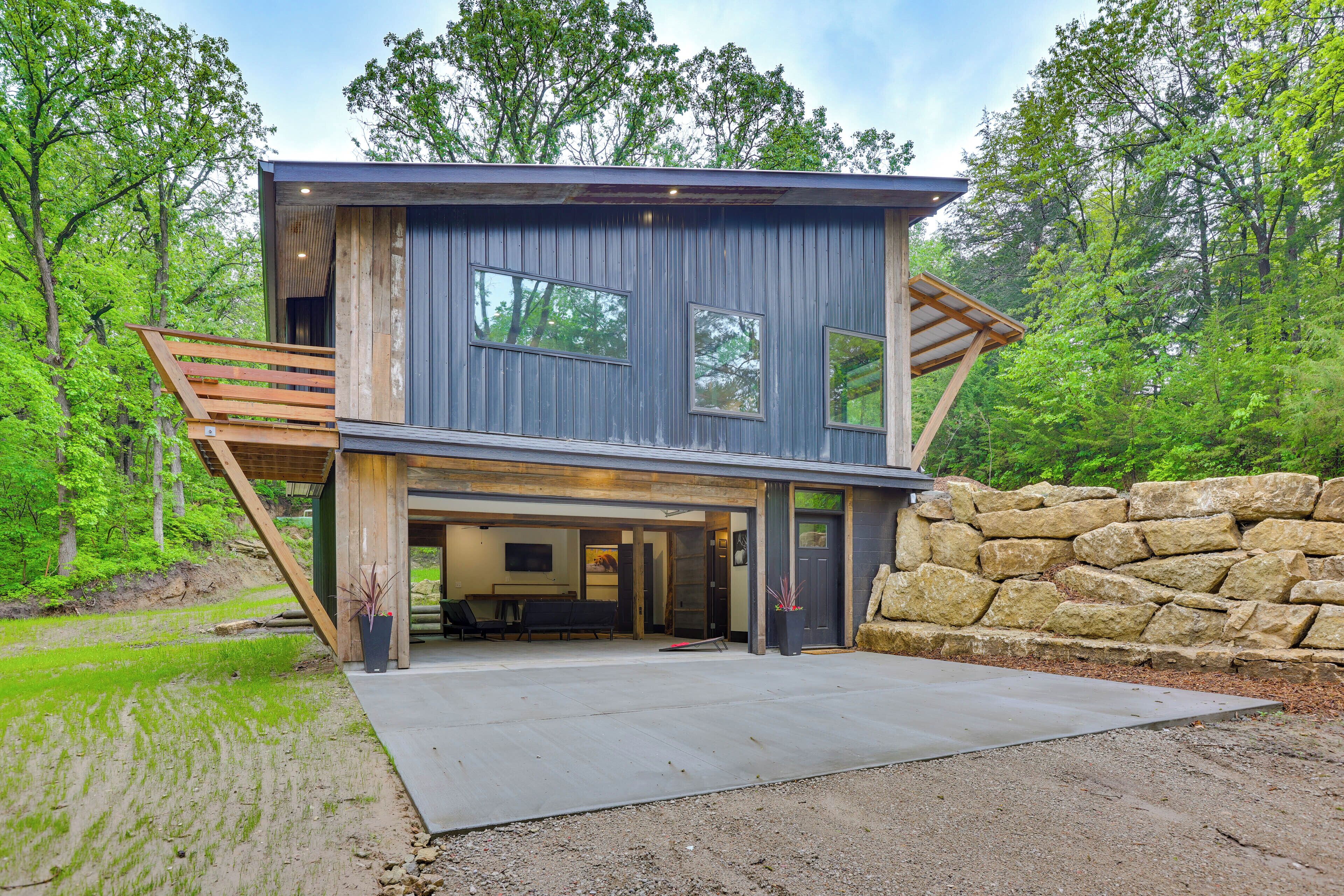 A modern two-story house with a garage, large windows, and a stone wall.