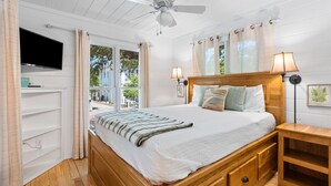 A bedroom with a bed, a ceiling fan, a TV mounted on the wall, and a window with curtains. - Beautiful Original Seaside Cottage + Swim & Tennis Club: Sleeps 6 (Santa Rosa Beach)