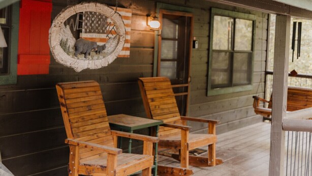 A rustic wooden porch with two wooden chairs and a small table.