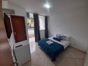 Et hotelværelse med seng, skrivebord og udsigt til det fri.