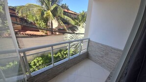 A balcony with a metal railing, a view of a street with buildings and palm trees, and a tiled floor. - Pousada Paraiso Barra da Tijuca (Rio de Janeiro)