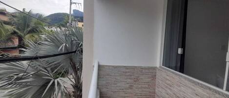 Un balcón con vista a palmeras y un edificio al fondo.