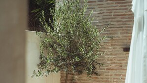 A patio with wooden furniture, a brick wall, and a potted plant. - La Maison Gaïa Hôtel & Spa (Torreilles)