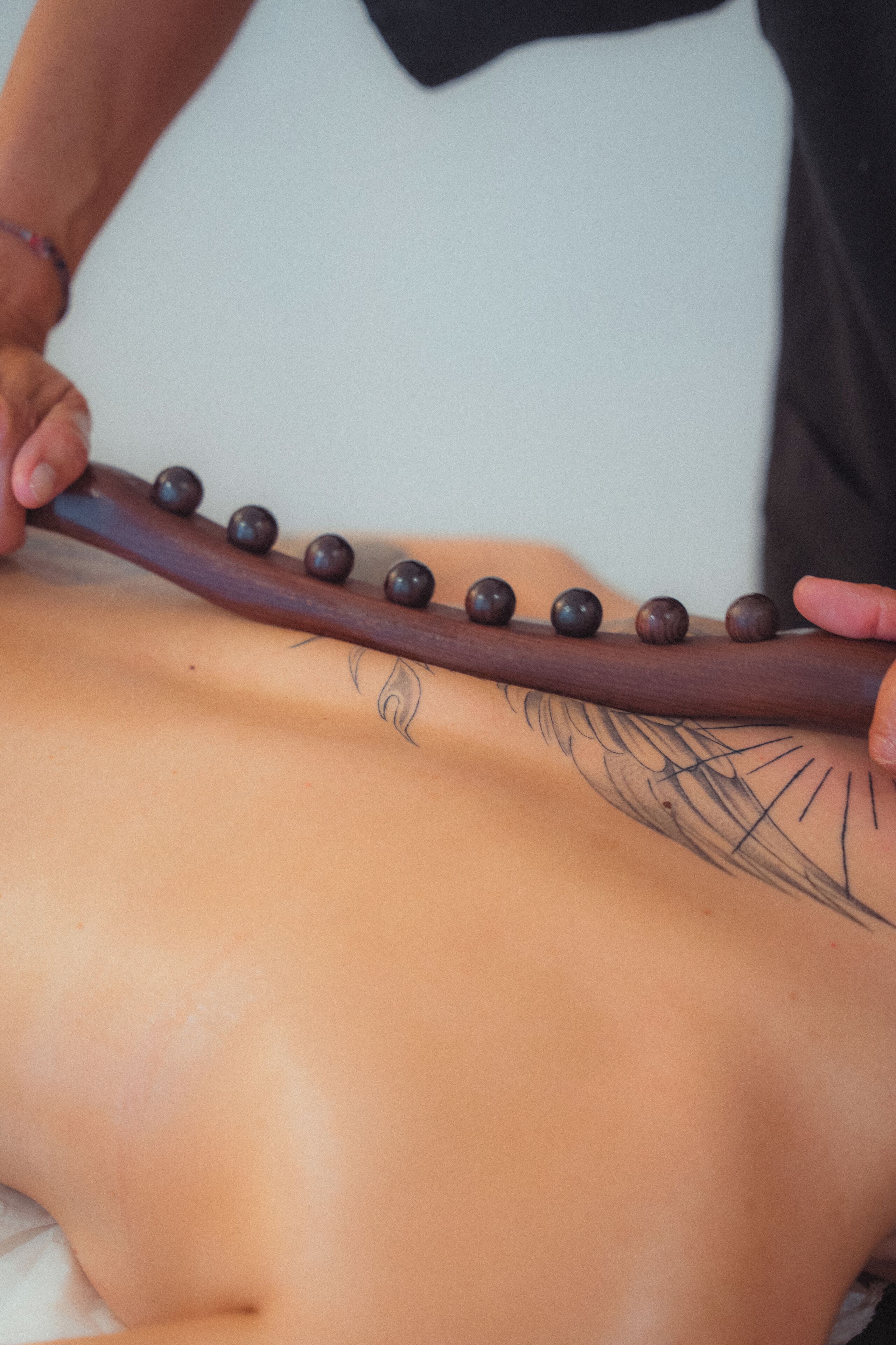 Een massageapparaat met houten knopen in gebruik op iemands rug.
