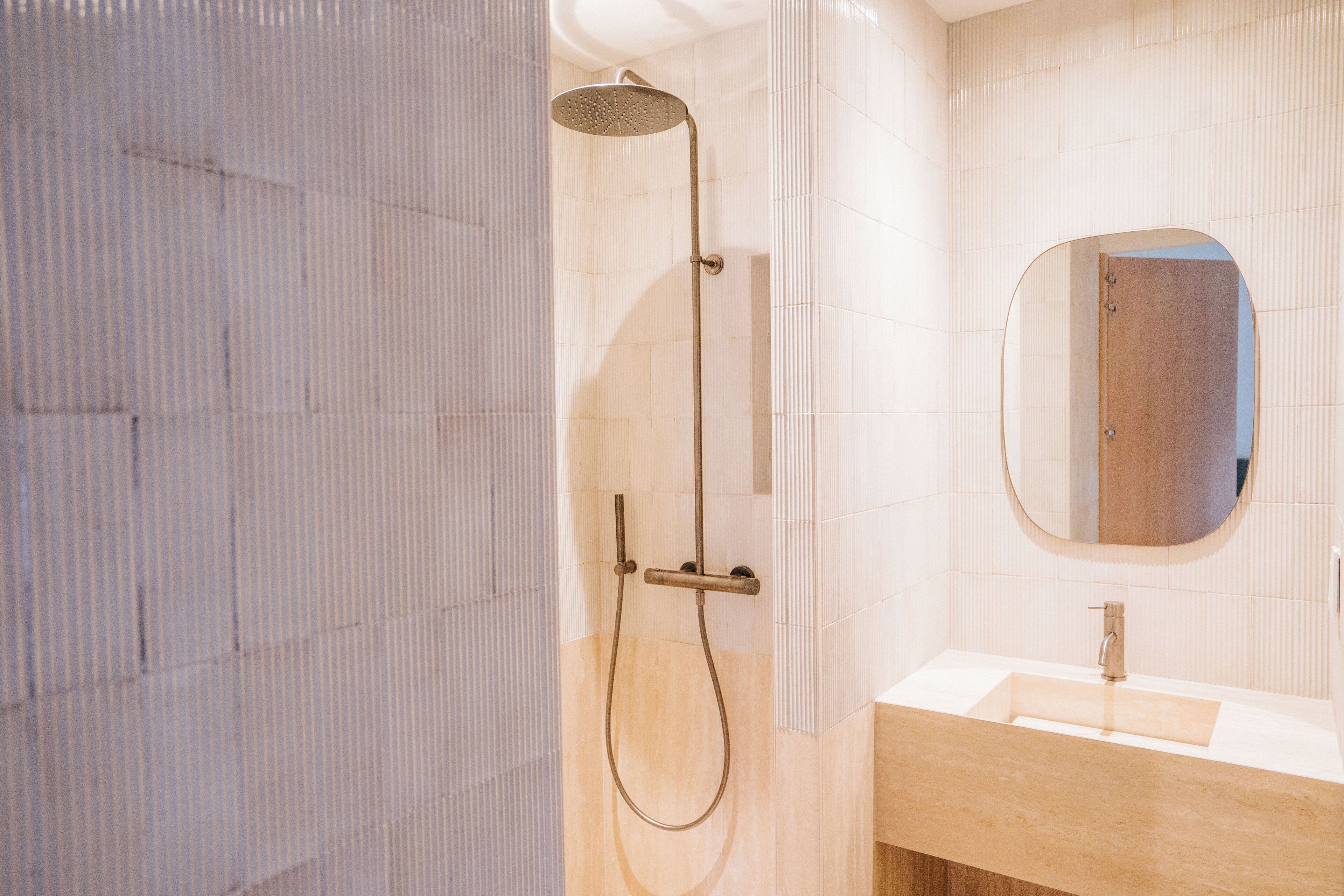 Un baño con ducha, lavabo y espejo.