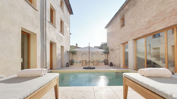 A spa area with two massage tables, a pool, and a covered seating area. - La Maison Gaïa Hôtel & Spa (Torreilles)