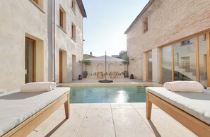 A spa area with two massage tables, a pool, and a covered seating area. - La Maison Gaïa Hôtel & Spa (Torreilles)