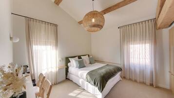 Une chambre à coucher avec un lit, un bureau avec une chaise et un luminaire suspendu.