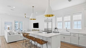 A modern kitchen with white cabinetry, a central island with bar stools, stainless steel appliances, and pendant lighting. - Beautiful Seacrest Home, Sleeps 16 - Lagoon Pool and Beach Tram Service (Panama City Beach)