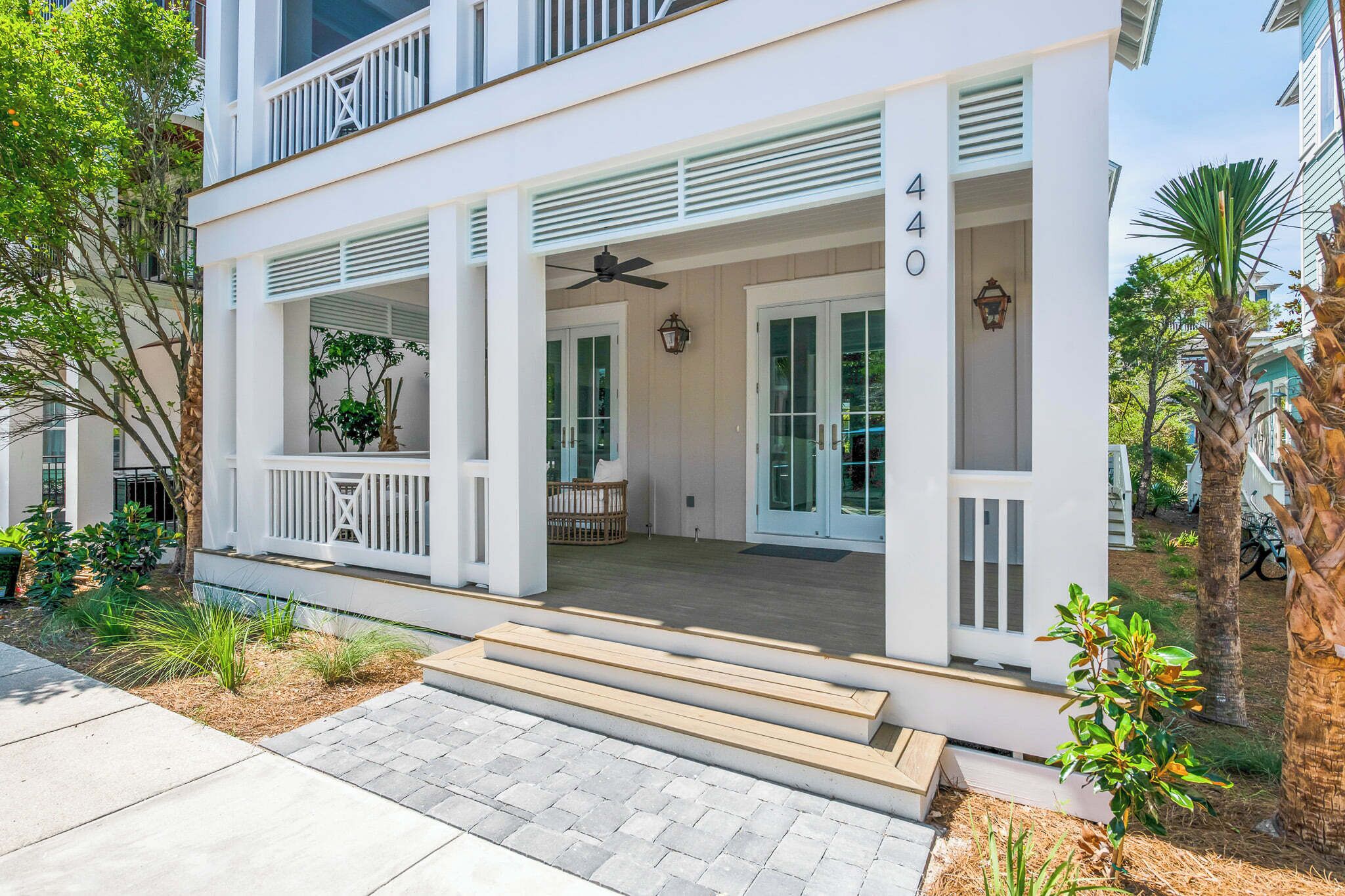 A two-story house with a covered porch, a balcony, and a number 440 sign.
