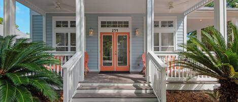 A two-story house with a porch, a double door with a number '22', and a staircase leading to the entrance.