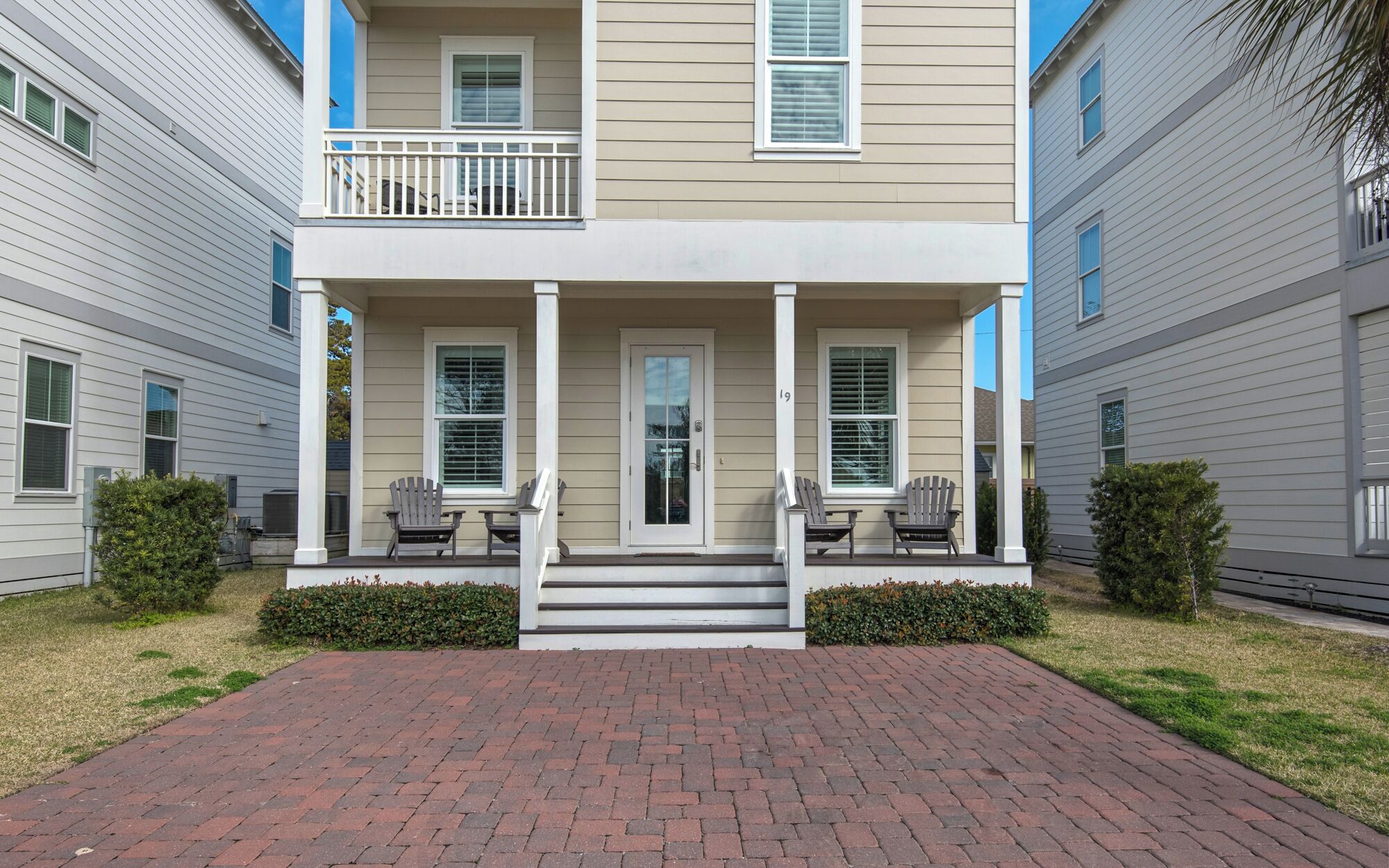A two-story residential building with a front porch, two windows on the ground floor, and a balcony on the second floor.