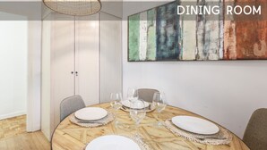 Een eetkamer met een ronde houten tafel, witte borden en wijnglazen.