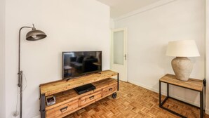 Een kamer met een houten tv-meubel, een flatscreen televisie, een lamp en een deur.
