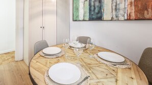 Een eetkamer met een ronde houten tafel, witte borden en wijnglazen.