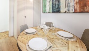 Comedor con una mesa redonda de madera, platos blancos y copas de vino.
