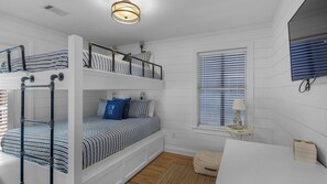 A bunk bed room with striped bedding, a small table with a lamp, and a window with blinds. - Classic Beach Home With Heated Private Pool - Sleeps 9 (Santa Rosa Beach)