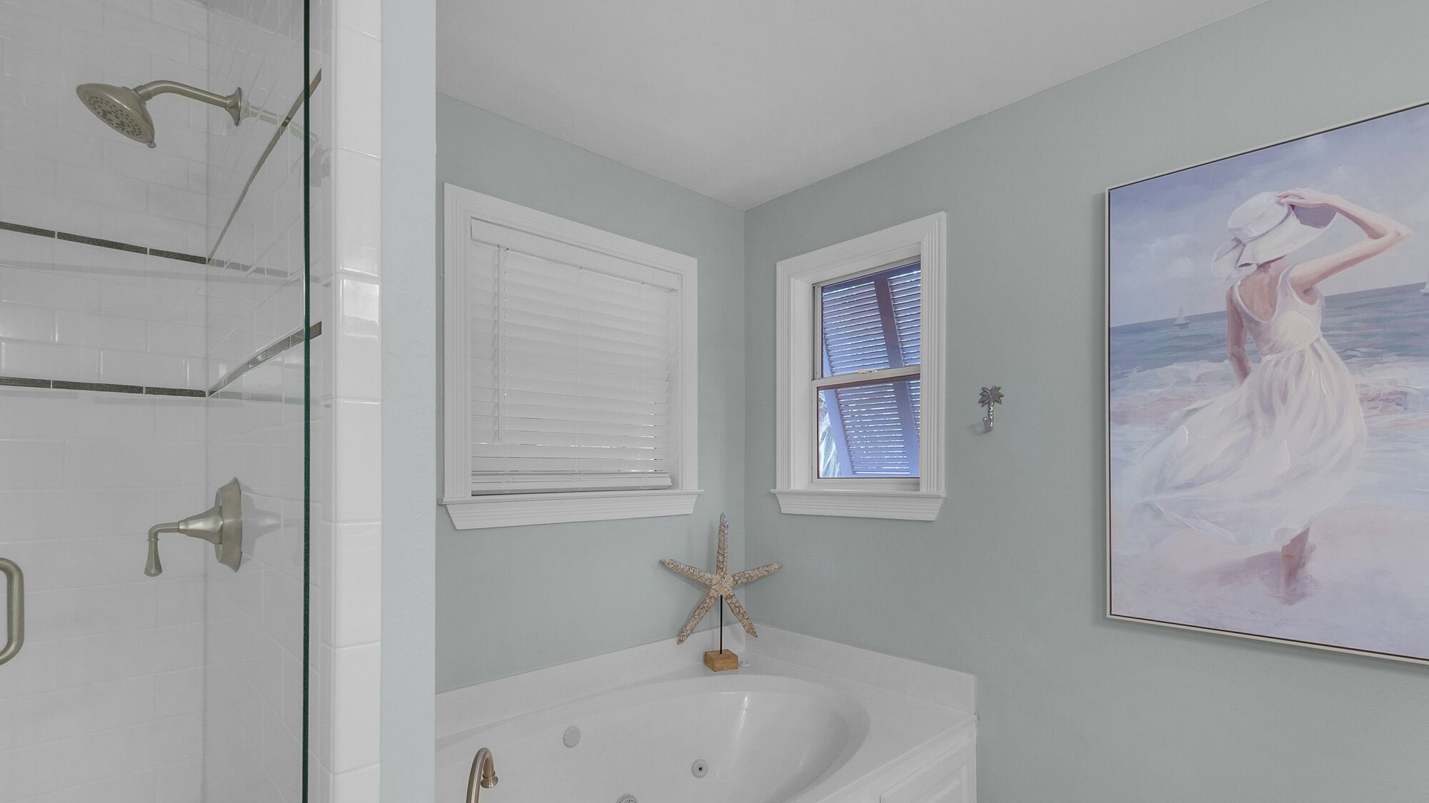 Un baño con bañera, ducha y ventana con persianas.
