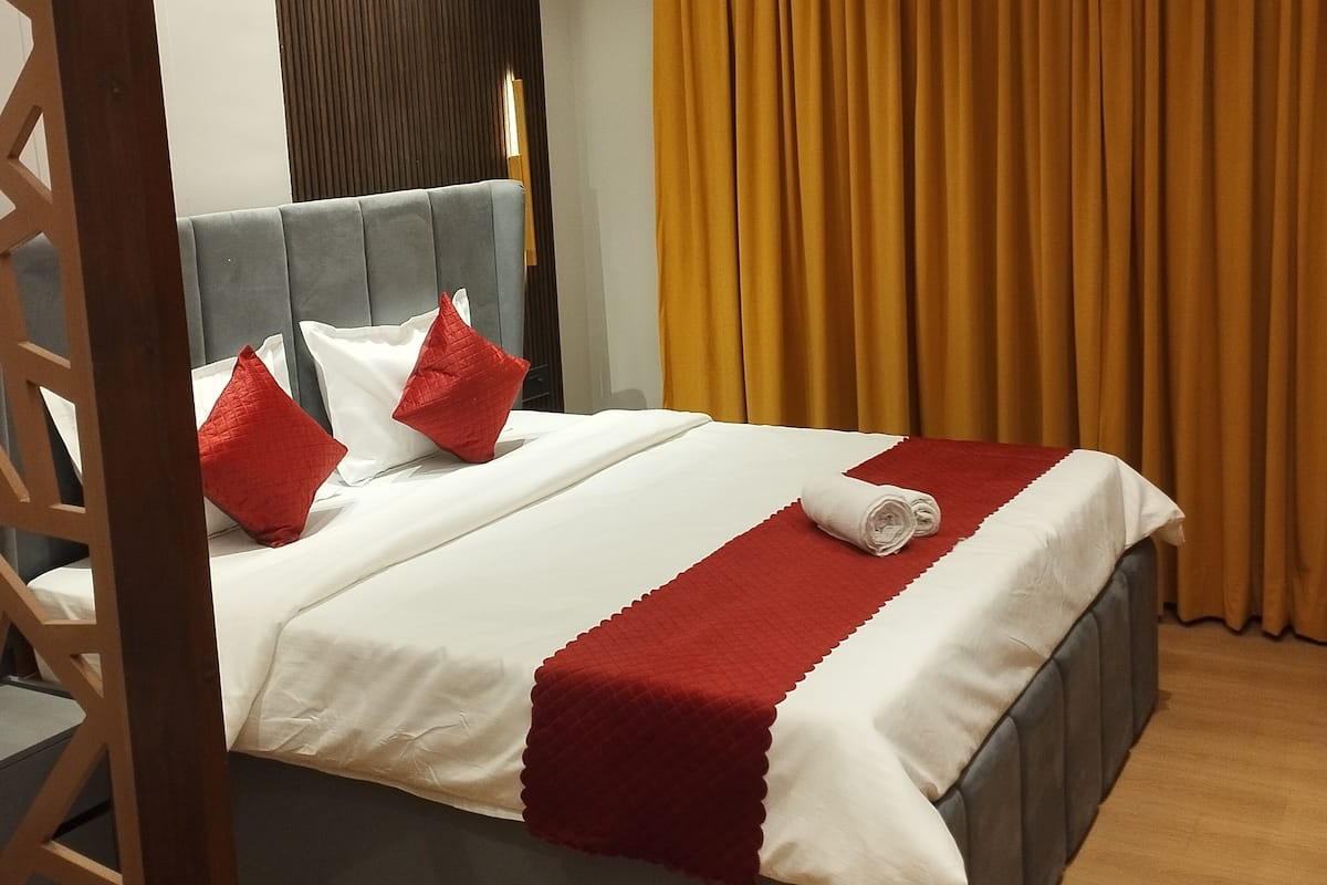 Una habitación de hotel moderna con una cama grande, un ventilador de techo, un equipo de aire acondicionado y un cabecero de madera.