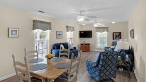 A spacious living room with a dining area, ceiling fans, and a flat-screen TV. - Classic Beach Retreat Just a Minute From the Beach Access in Seacrest on 30A (Panama City Beach)