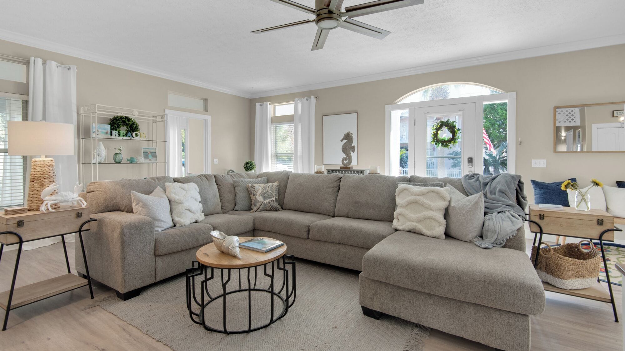 A modern living room with a sectional sofa, a round coffee table, and a ceiling fan.