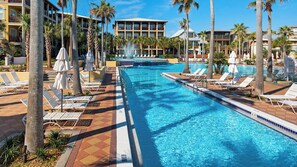 A swimming pool with lounge chairs and umbrellas, surrounded by palm trees and hotel buildings. - Close to Beach Access & Rosemary~ Seacrest Lagoon Pool Access (Panama City Beach)