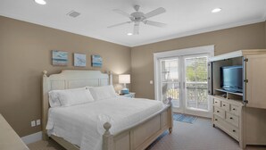 Une chambre à coucher avec un lit, une table de chevet, un téléviseur et un ventilateur de plafond.