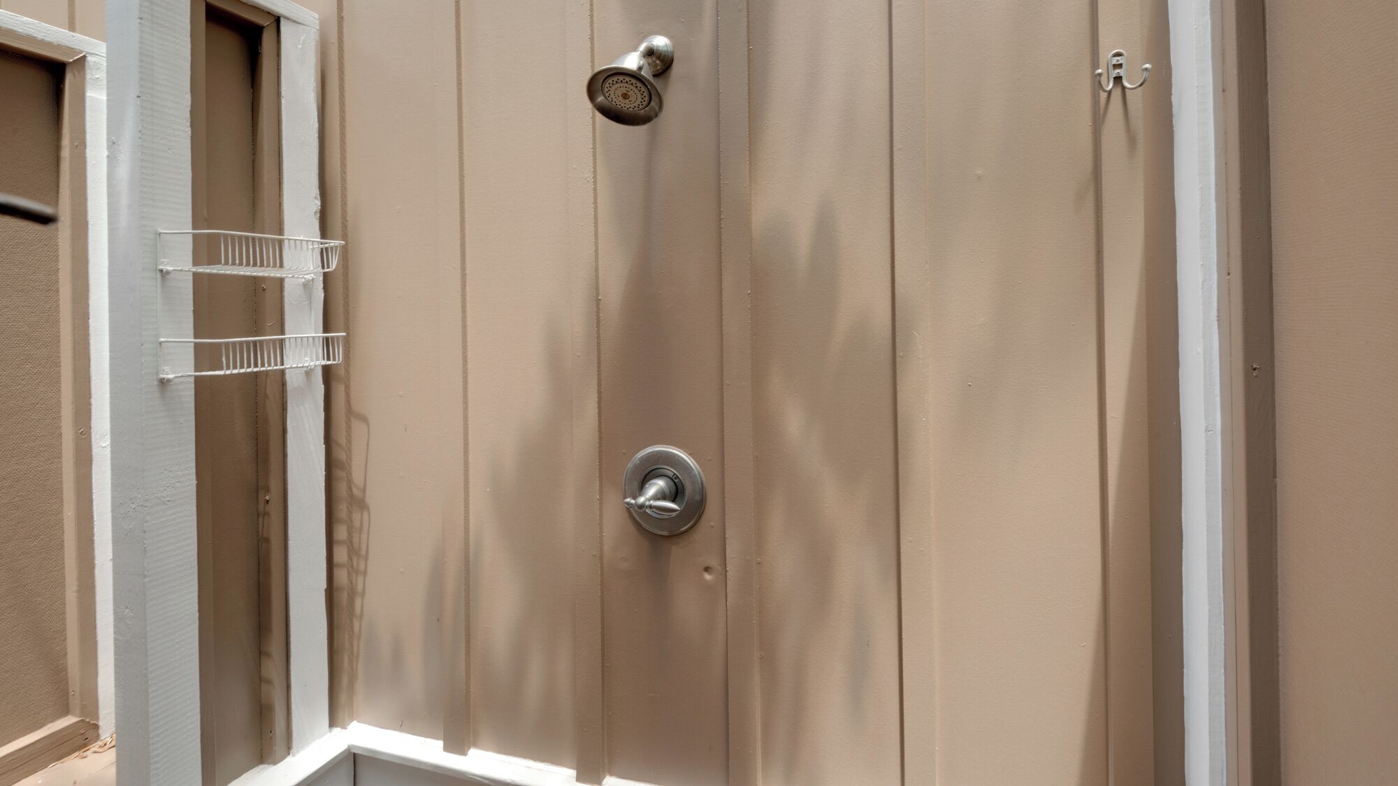 A shower enclosure with a showerhead and a control knob.