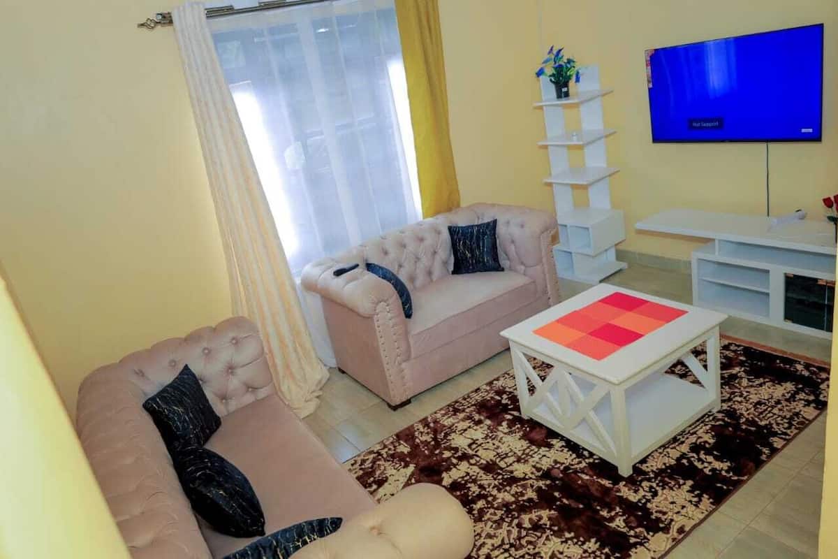 A living room with two sofas, a coffee table, a TV, and a white shelving unit.