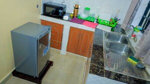 A compact kitchen with a refrigerator, microwave, sink, and various kitchen utensils. - Lux Suites Rubi Homes Kisii (Kisii)