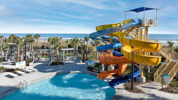 A water park with multiple slides, a pool, and a beach view.