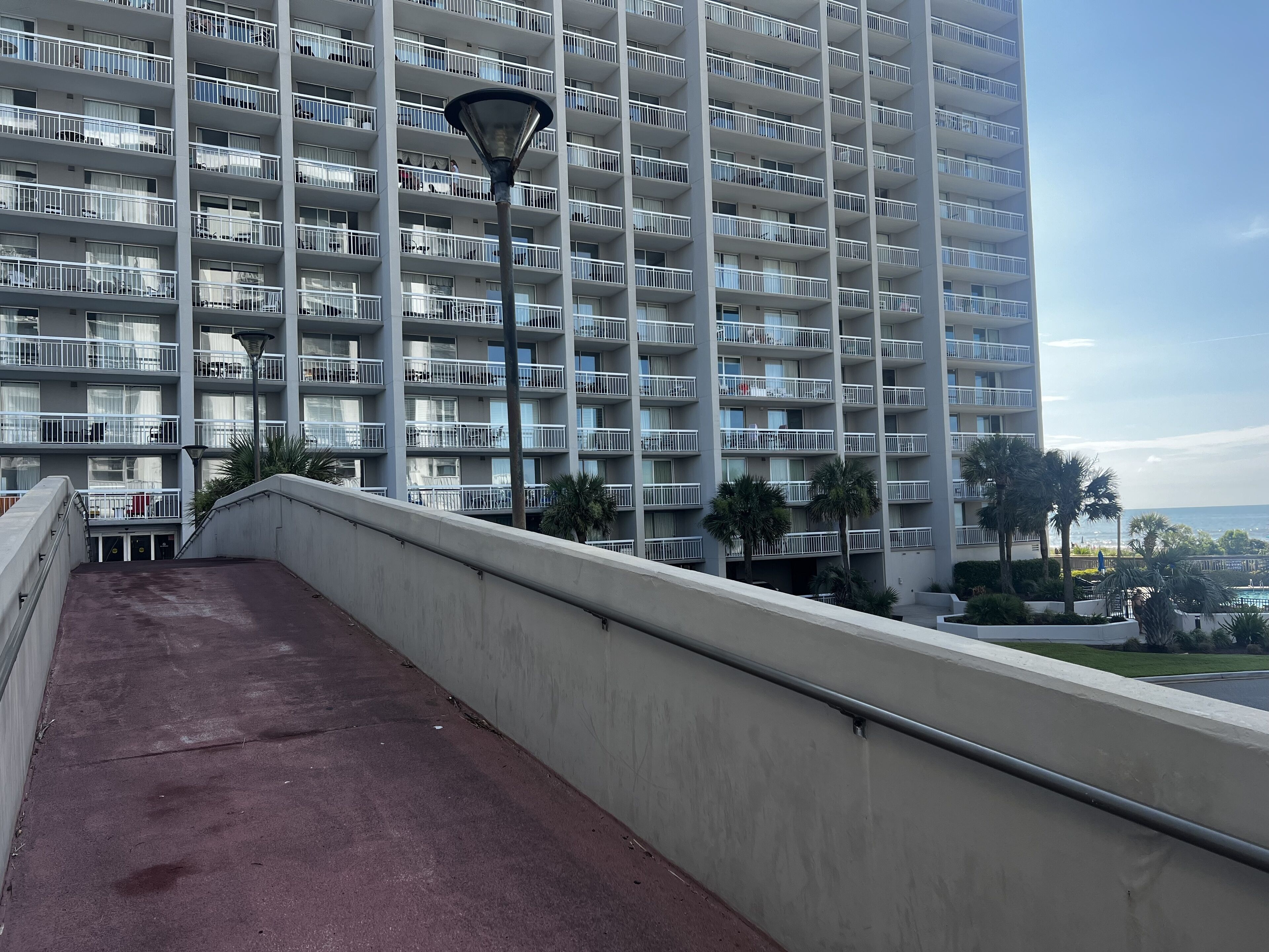 A high-rise building with multiple balconies, a concrete walkway, and a street lamp.