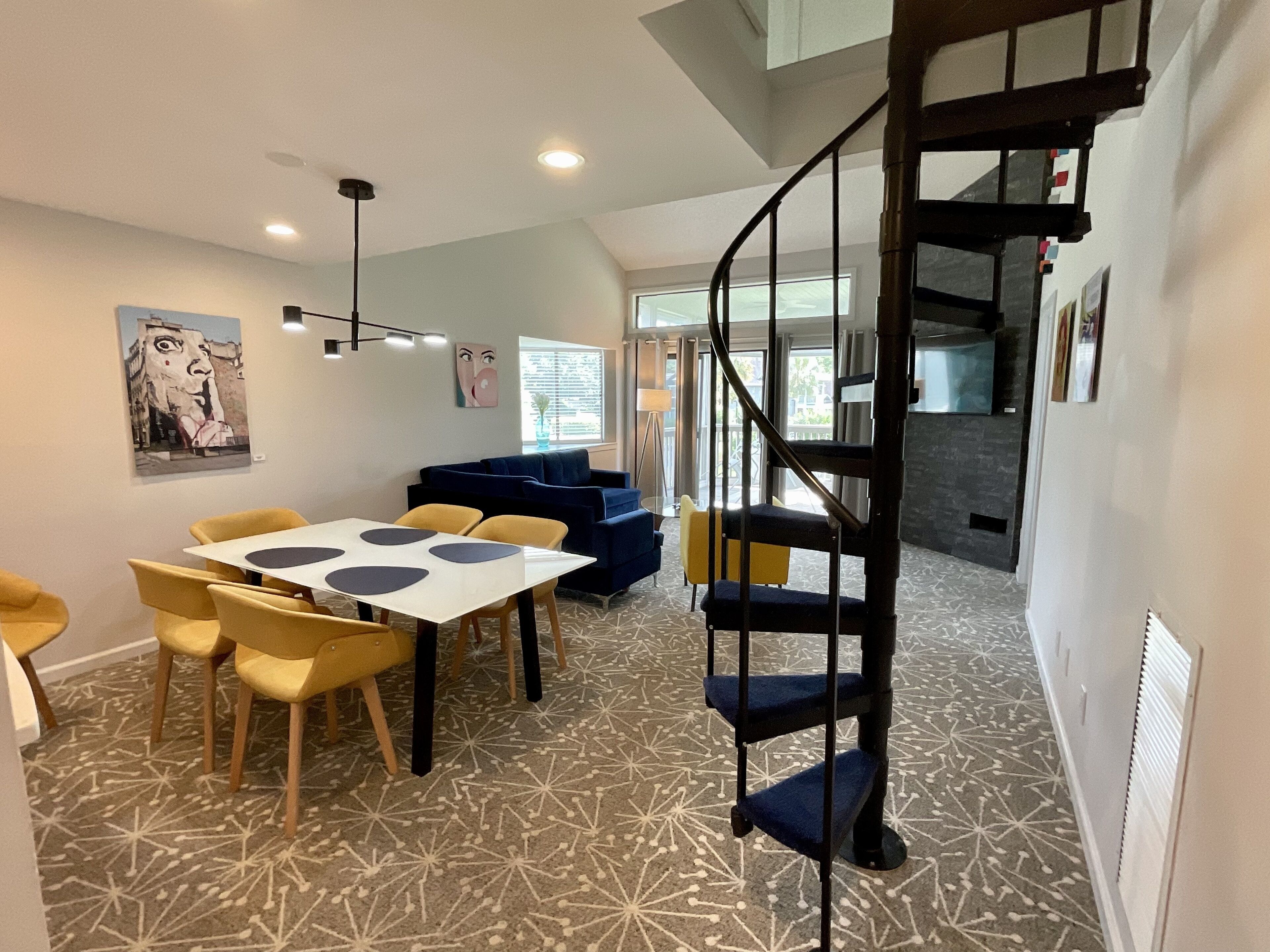 A modern interior with a dining area, a blue sofa, and a spiral staircase.