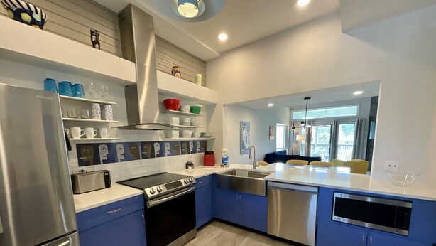 Una cucina moderna con mobili blu, elettrodomestici in acciaio inossidabile e una grande isola.
