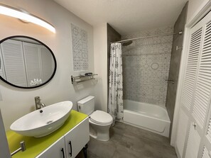 Ein modernes Badezimmer mit einem großen, ovalen Waschbecken, Toilette und Badewanne.